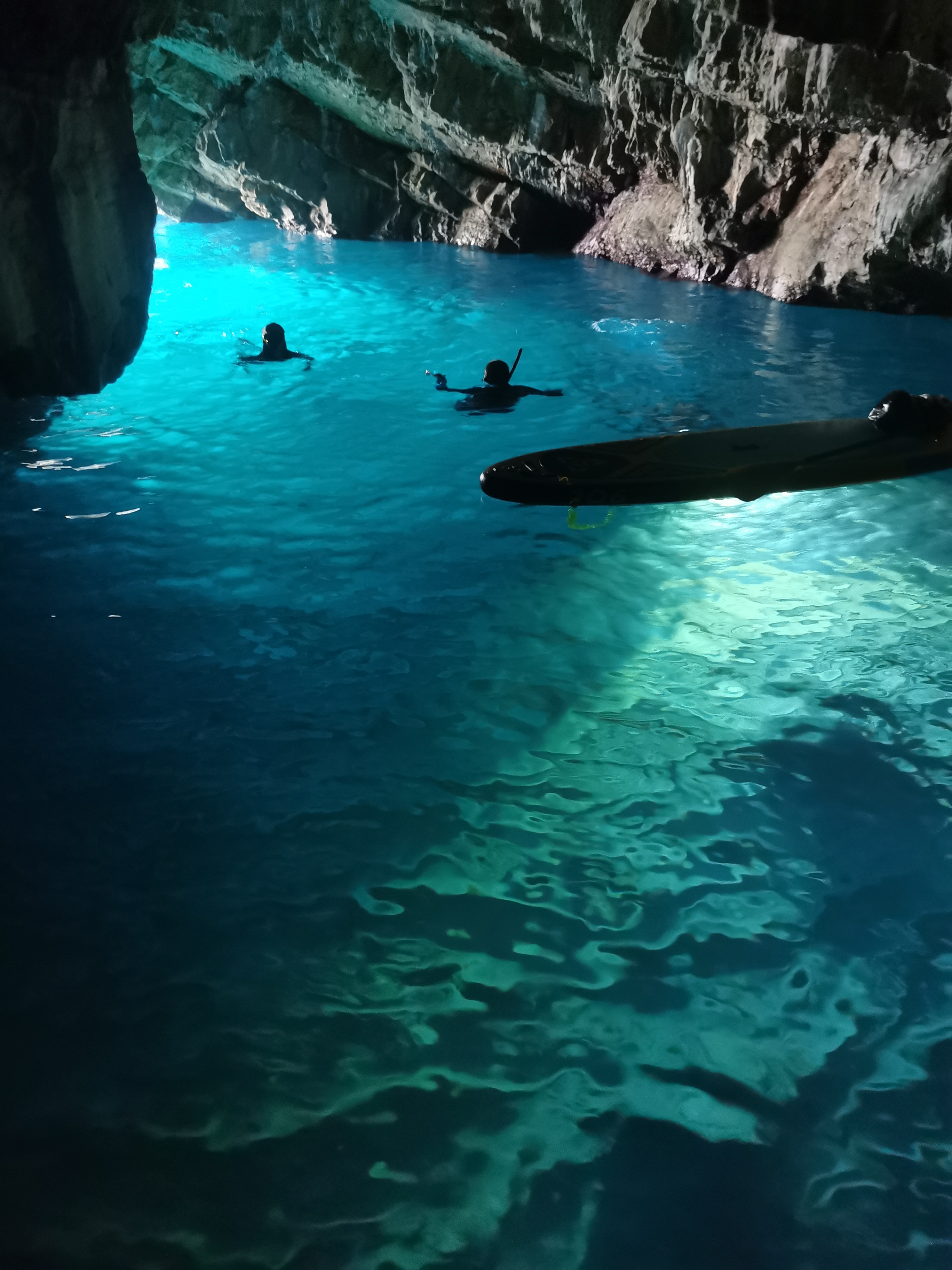 Snorkellers in the electric-blue glow of the sea cave