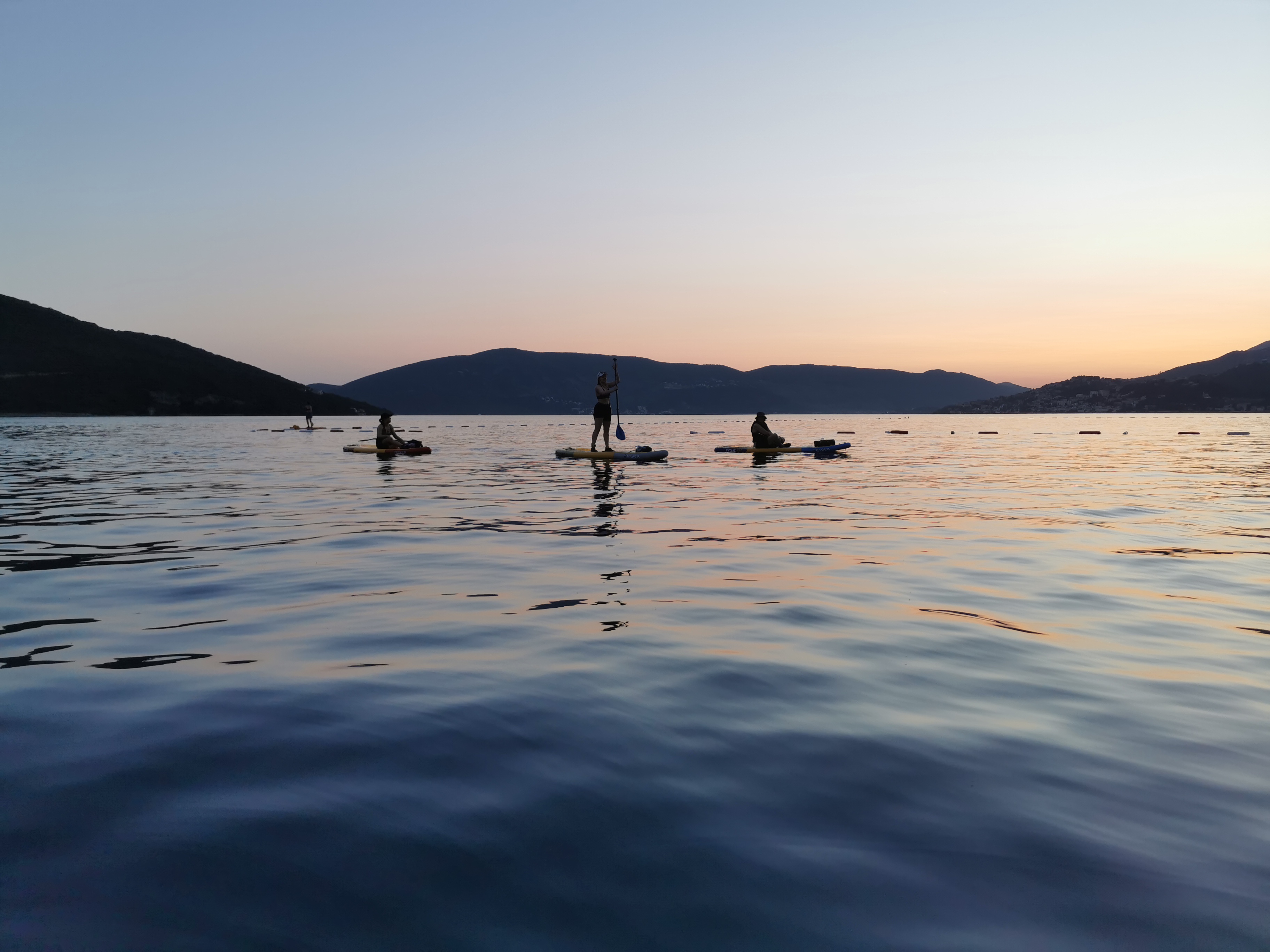 SUP paddleboarders silhouetted at sunset on the Bay of Kotor