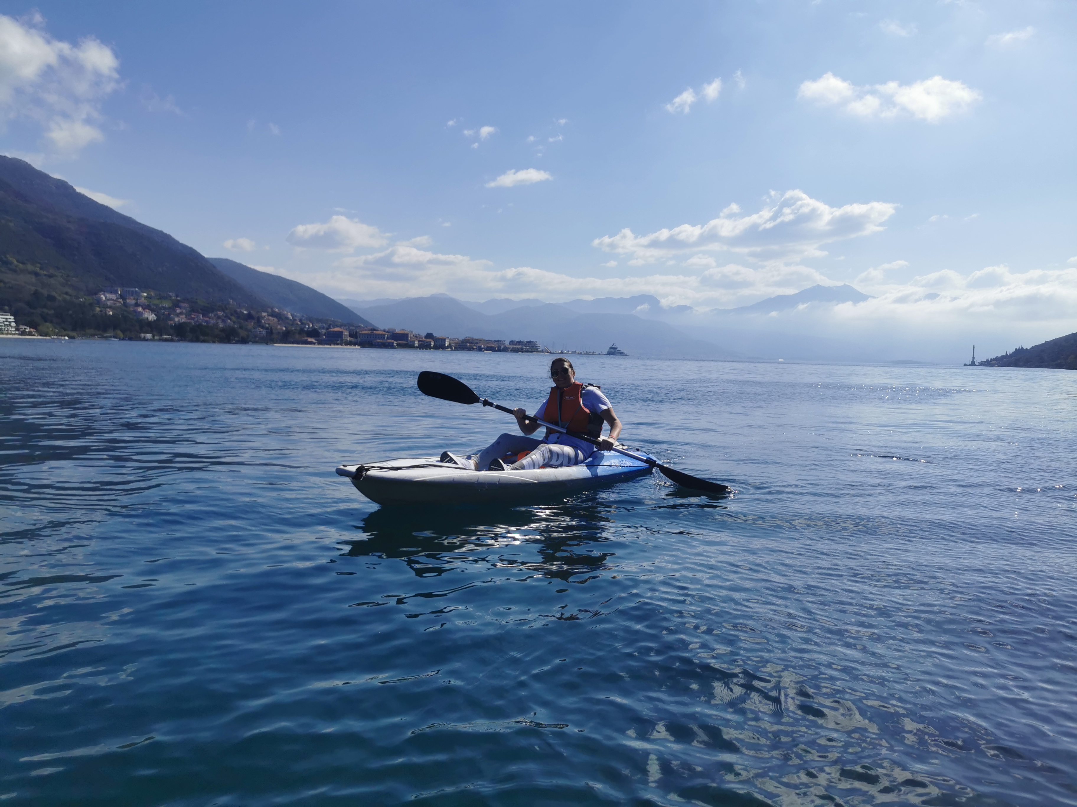 Solo kayaker on crystal-clear bay below the Herceg Novi mountains