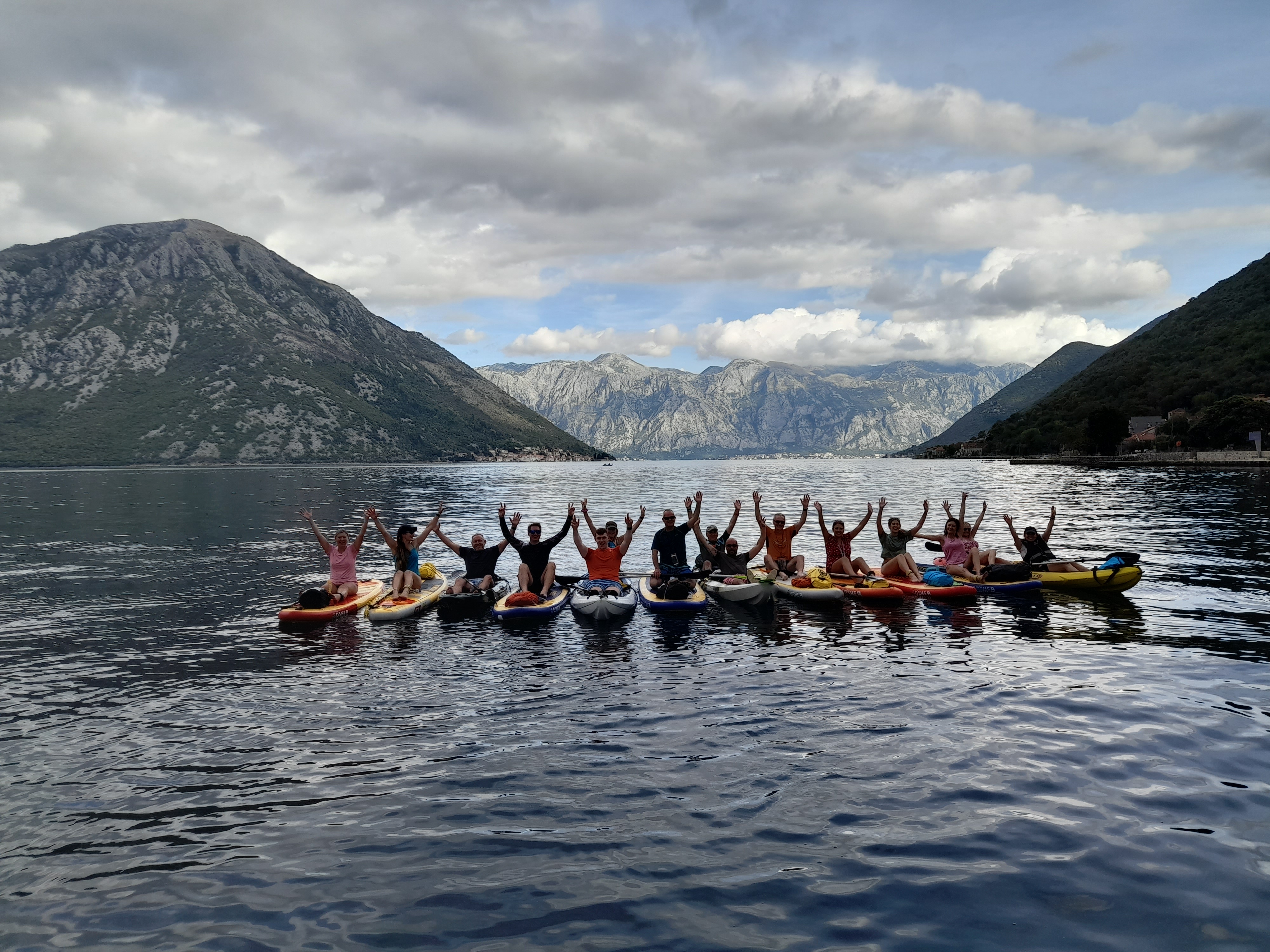 Large group raising hands on boards with the Bay of Kotor panorama